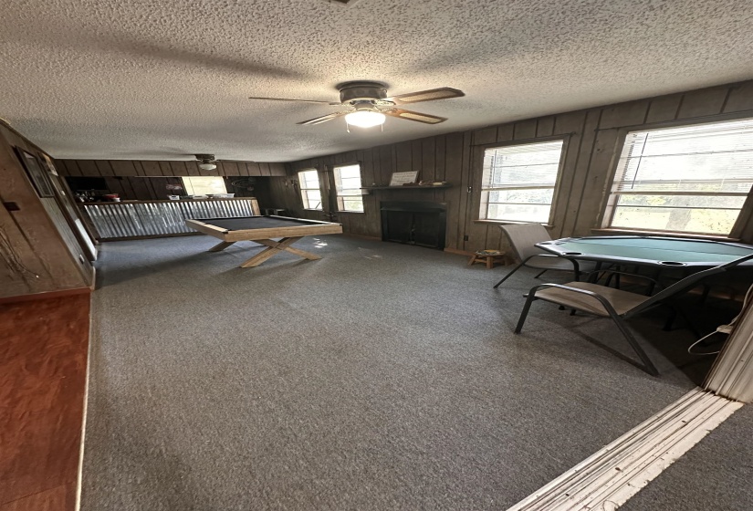 Spacious room featuring paneled walls, a built-in fireplace, and multiple windows