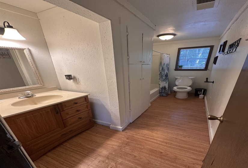 Bathroom featuring a wood-finish vanity with an integrated sink, a framed mirror, and warm-toned flooring