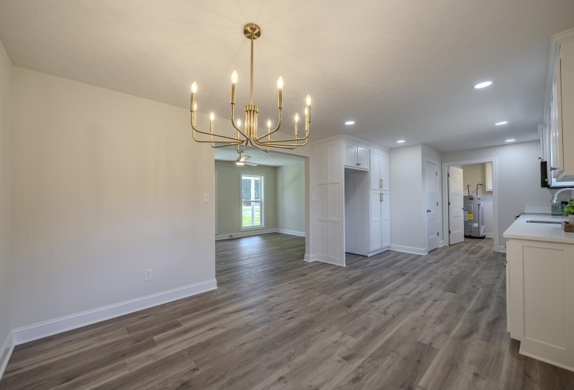 Spacious interior featuring wood-finish flooring throughout, recessed lighting, and a modern brass chandelier