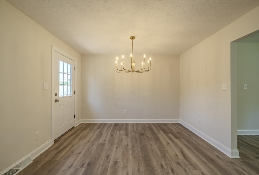 Room featuring wood-finish flooring, a contemporary gold-tone chandelier, a white door with multiple glass panes, and crisp white trim