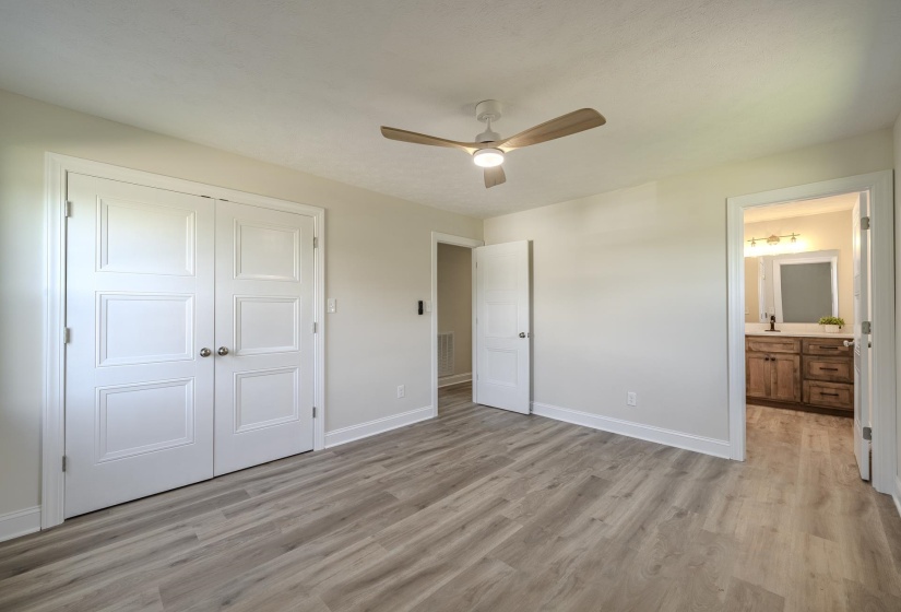 Spacious room featuring wood-finish flooring, light-colored walls, and a contemporary ceiling fan with integrated lighting