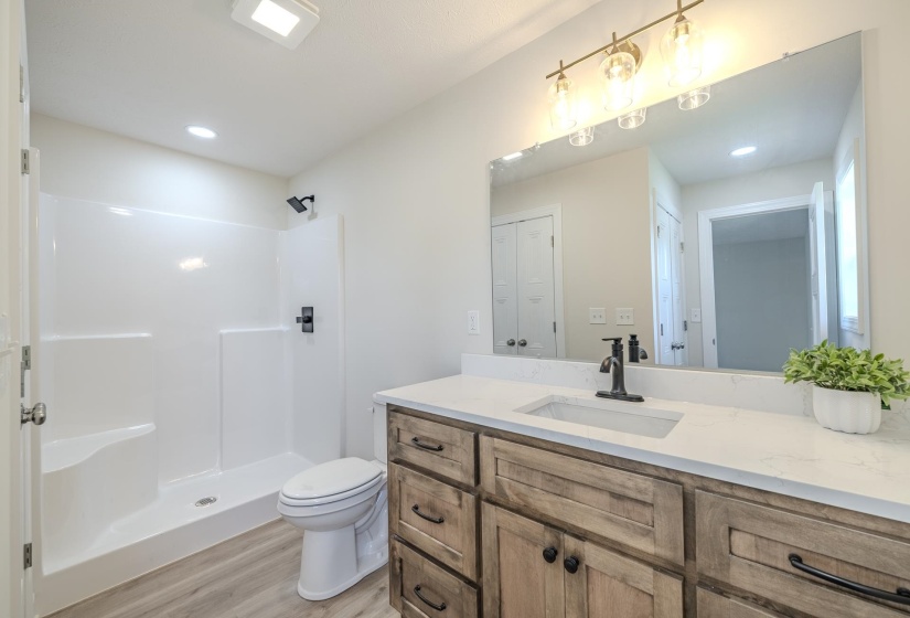 Bathroom featuring a wood-finish vanity with a light-toned countertop, a rectangular undermount sink, and black fixtures