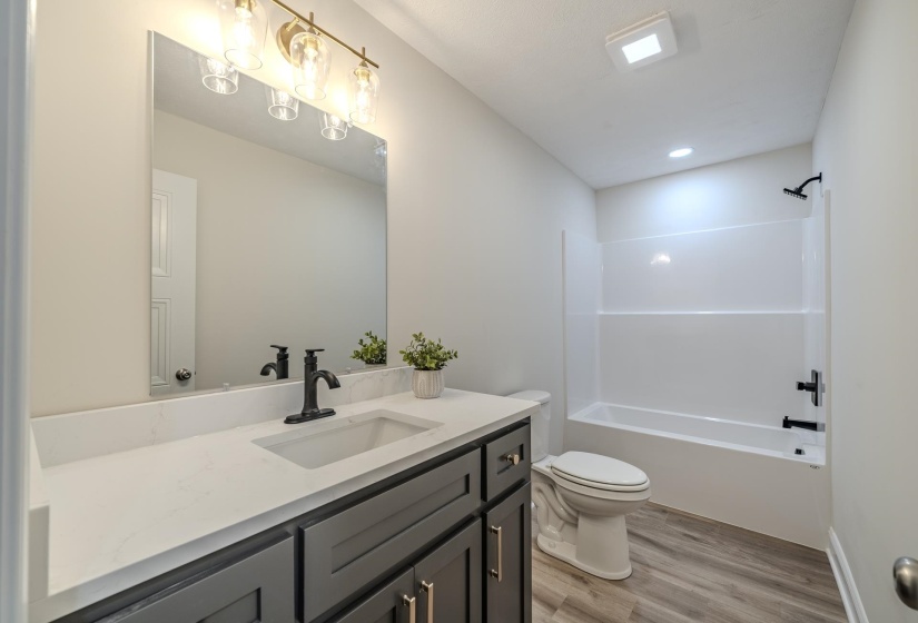 Bathroom featuring a dark gray vanity with a light-toned countertop, a rectangular undermount sink, and matte black fixtures