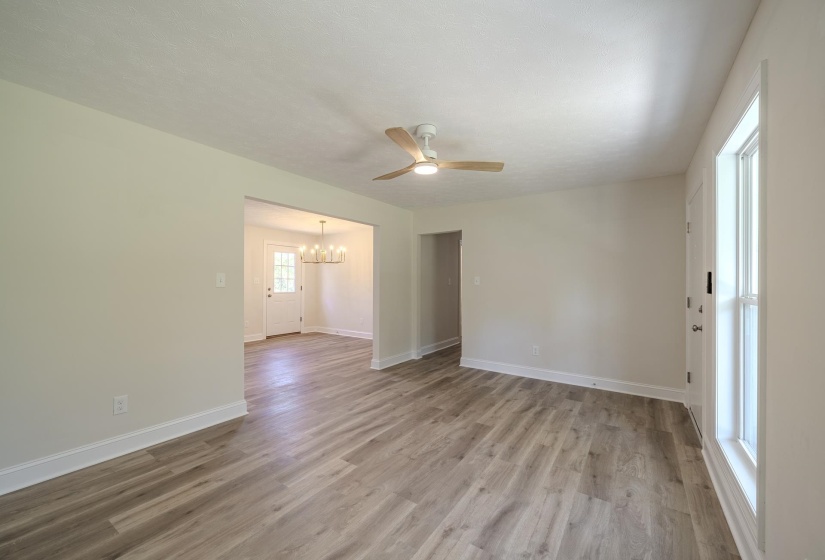 Spacious interior featuring wood-finish flooring, light neutral wall paint, and a contemporary ceiling fan
