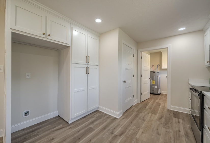 Kitchen area featuring wood-finish flooring, recessed lighting, and white shaker-style cabinetry with gold-tone hardware