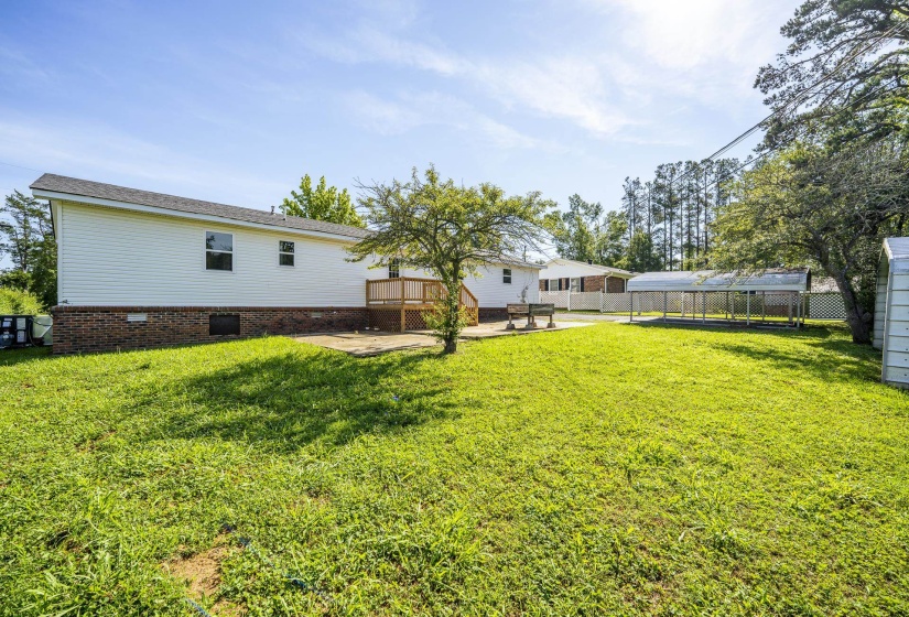 Spacious lawn with a white vinyl-sided home featuring a brick foundation