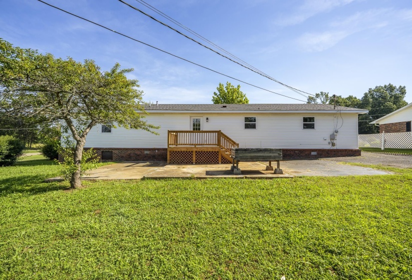 Rear exterior featuring white siding and a wood deck