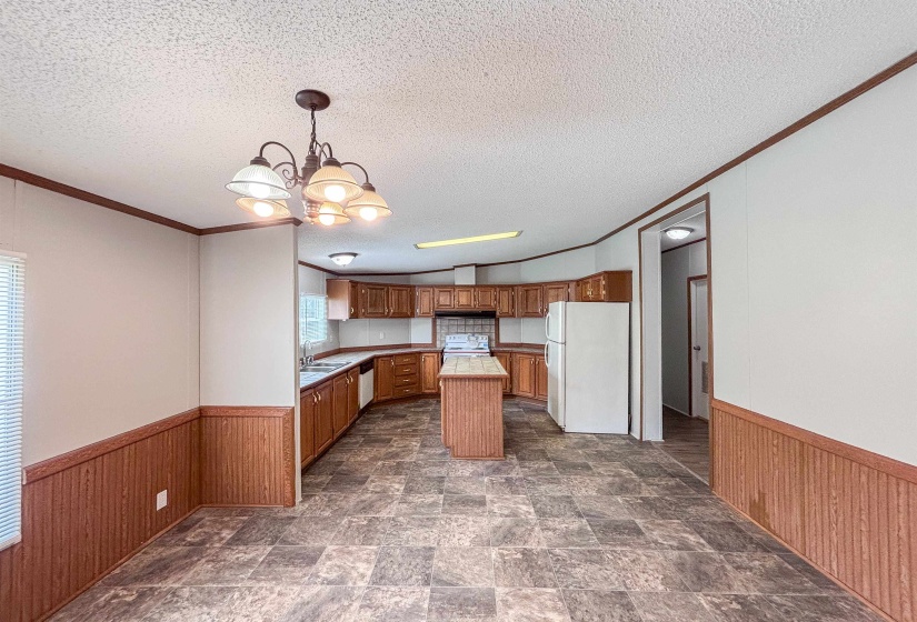 Open-concept kitchen and dining area featuring a central island, wood-finish cabinetry, and durable tile-look flooring