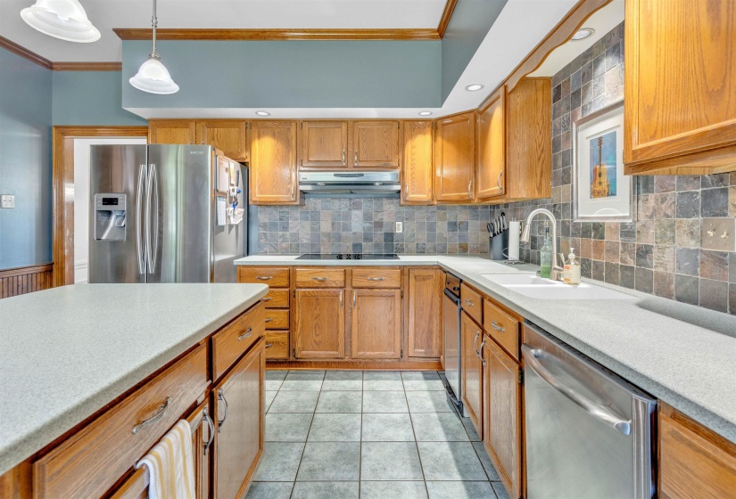 Kitchen with wood cabinetry, gray-toned tile flooring, and light-colored countertops