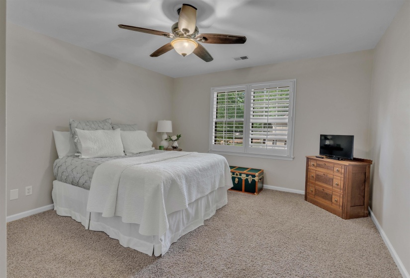 Carpeted room featuring a ceiling fan with light fixture, window with plantation shutters, and light neutral wall paint