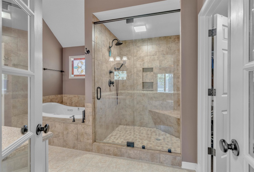 Spacious bathroom featuring a large walk-in shower with glass enclosure, built-in bench, and dual shower heads