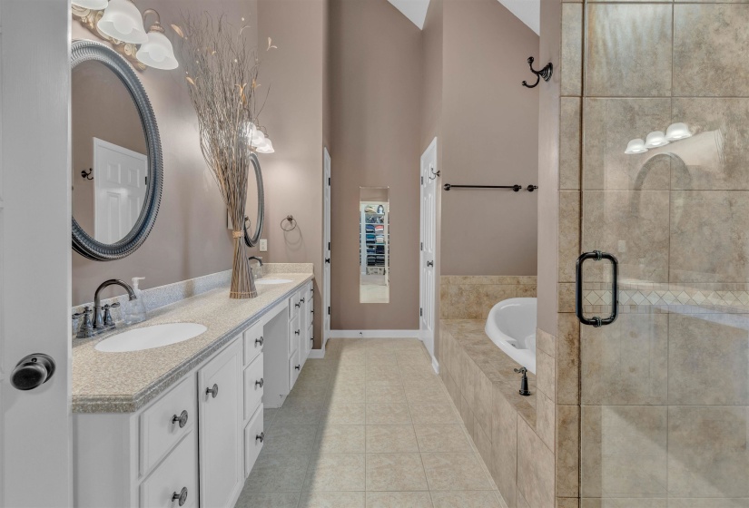 Spacious bathroom featuring a dual vanity with light-toned countertops, white cabinetry, and oval mirrors