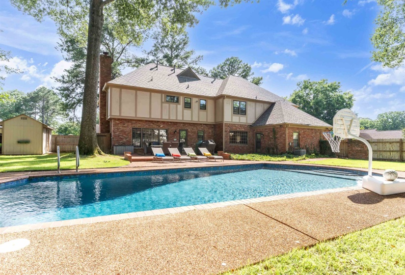 Expansive backyard featuring a rectangular swimming pool with exposed aggregate coping