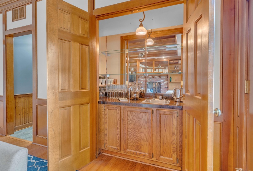 Custom wet bar featuring wood-finish cabinetry, a sink, and pendant lighting