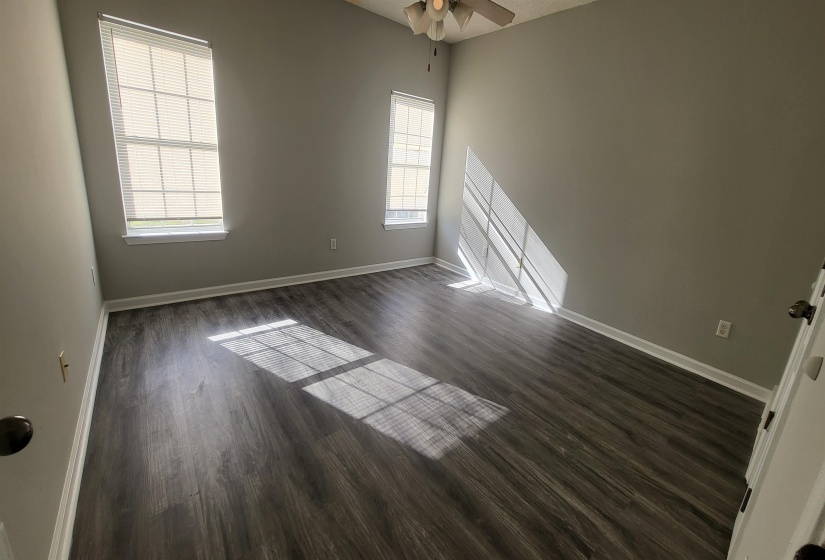 Empty room with ceiling fan, a healthy amount of sunlight, and dark hardwood / wood-style floors