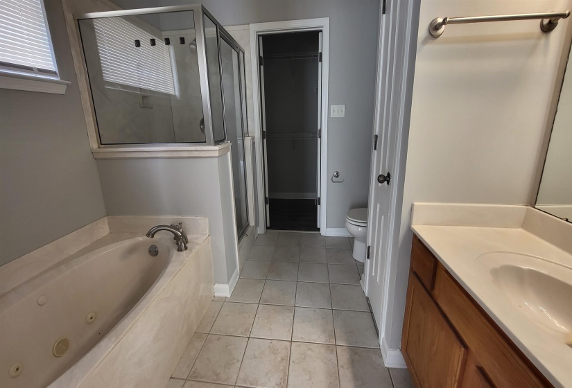 Full bathroom with tile patterned flooring, vanity, shower with separate bathtub, and toilet