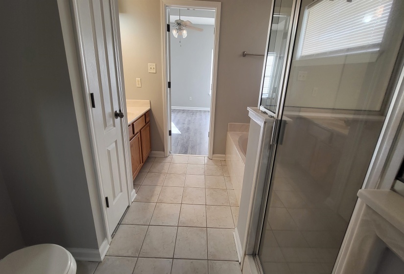 Full bathroom with tile patterned floors, vanity, ceiling fan, shower with separate bathtub, and toilet