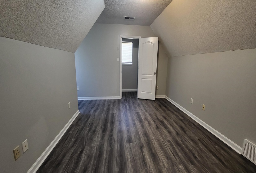 Bonus room with a textured ceiling, dark hardwood / wood-style flooring, and vaulted ceiling