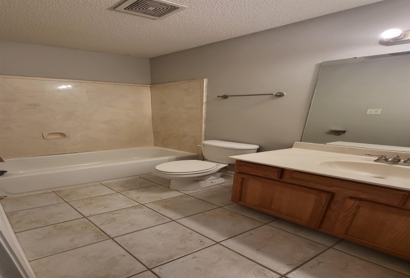 Full bathroom with tile patterned floors, vanity, toilet, and a textured ceiling