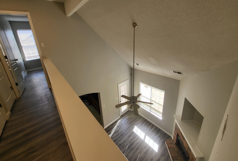 Stairway with a brick fireplace, a textured ceiling, ceiling fan, wood-type flooring, and high vaulted ceiling