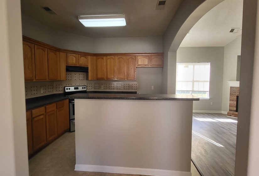 Kitchen featuring backsplash, a fireplace, stainless steel electric range oven, and light hardwood / wood-style flooring