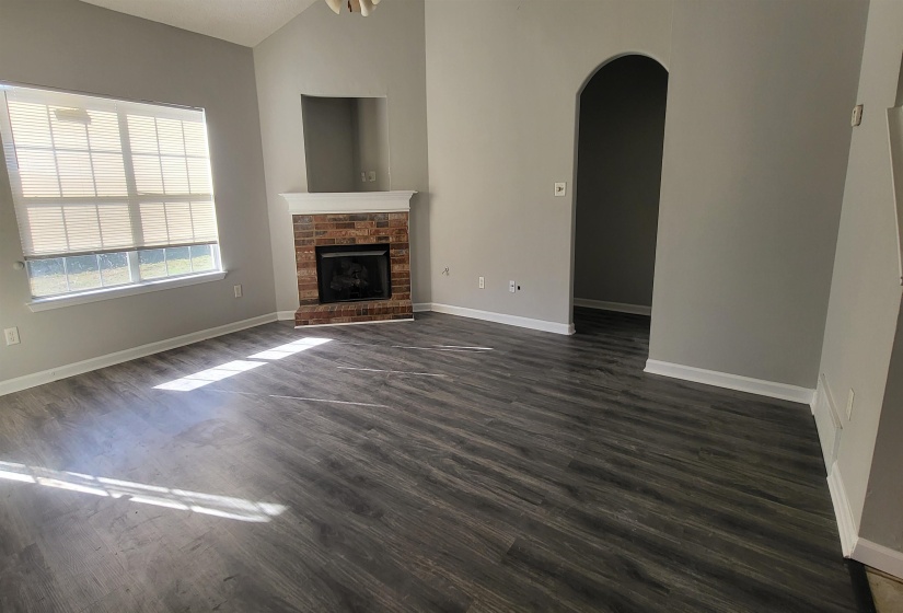 Unfurnished living room with dark hardwood / wood-style flooring, a fireplace, and vaulted ceiling