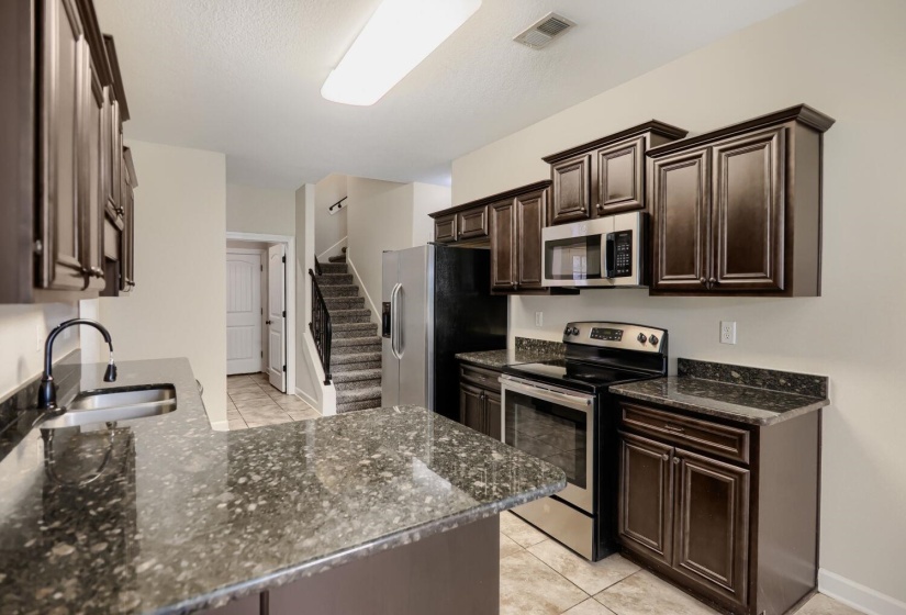 Kitchen featuring dark wood cabinetry, speckled countertops, and stainless steel appliances