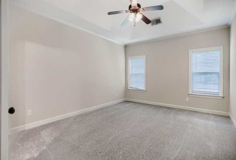 Spacious room featuring gray carpeting, light-toned walls, and a tray ceiling