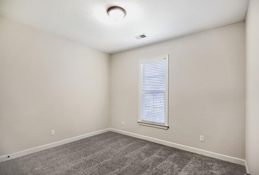 Neutral tone paint throughout, featuring a single window with blinds, recessed lighting, and grey textured carpeting