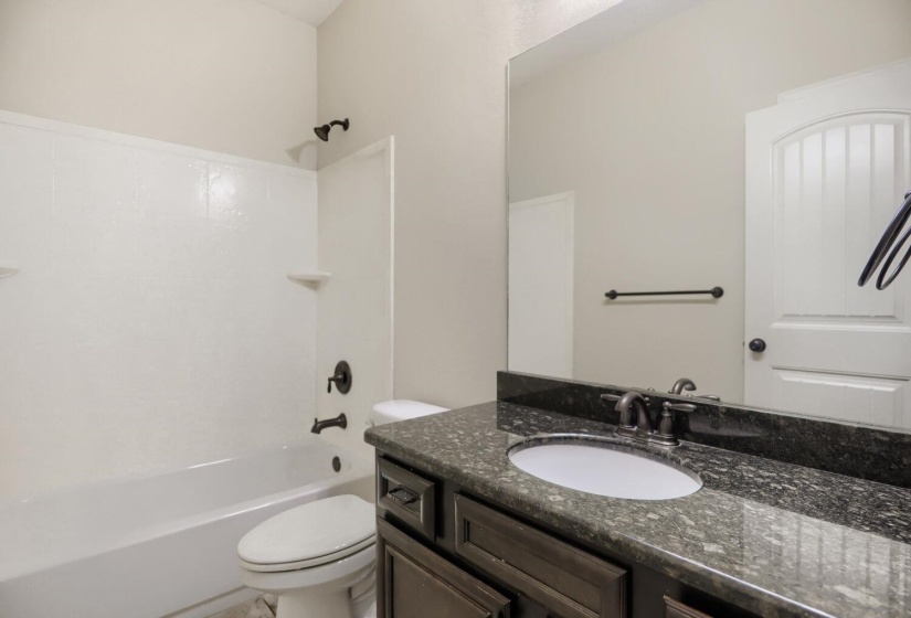 Bathroom featuring a dark wood vanity with an undermount sink, dark stone countertop, and oil-rubbed bronze fixtures