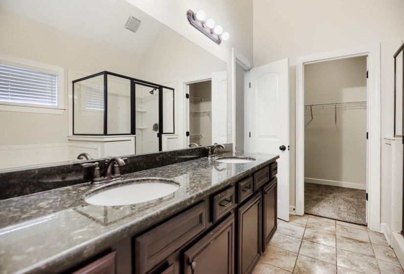 Double vanity with dark wood cabinetry and a speckled countertop
