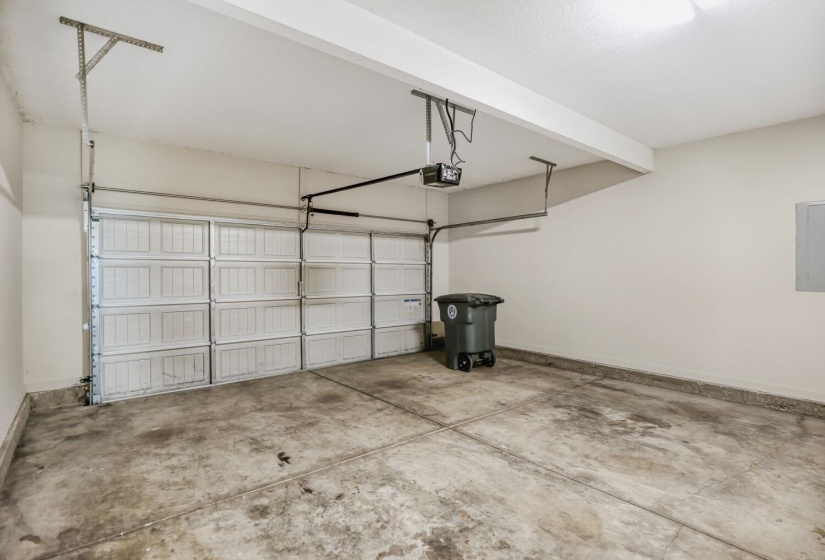 Attached garage with a sectional overhead door, exposed concrete flooring, and ceiling-mounted lighting