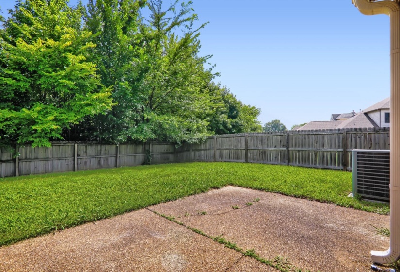 Expansive backyard featuring a manicured lawn, a concrete patio, and a wood privacy fence