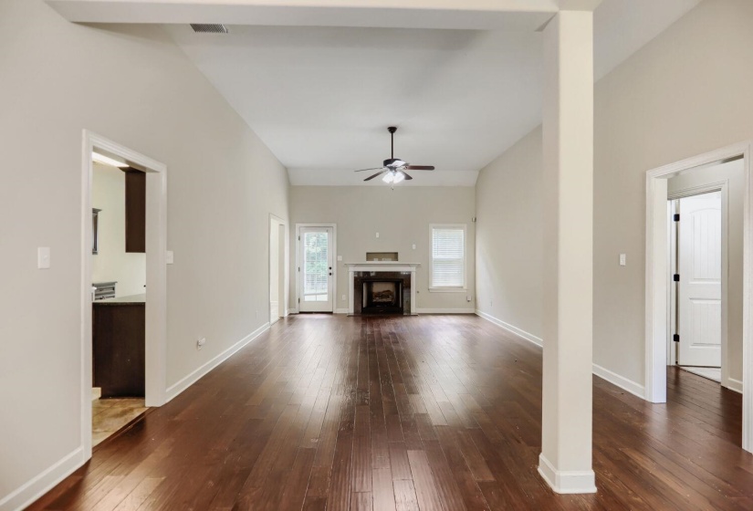 Spacious living area featuring wood-finish flooring, vaulted ceilings, and a ceiling fan