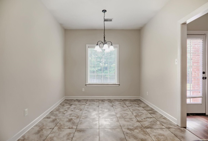 Dining space featuring a four-light chandelier, a window with blinds, and tile flooring
