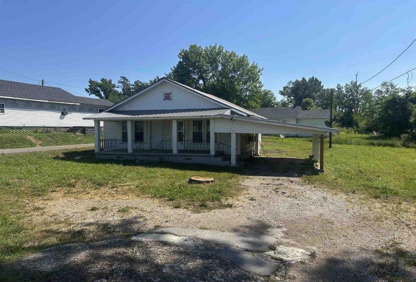 White-sided residence featuring a covered front porch with railings, a metal roof, and an attached carport