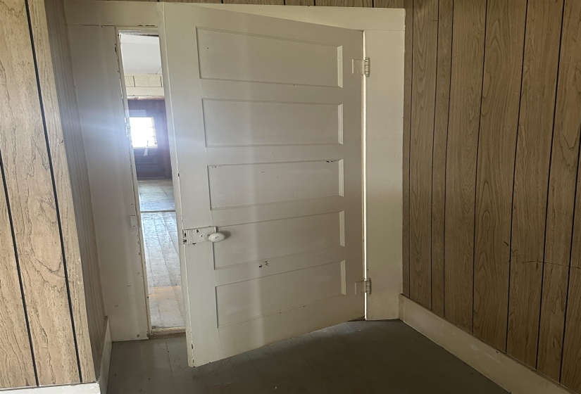 White paneled door with a round knob, featuring visible hinges and a white frame