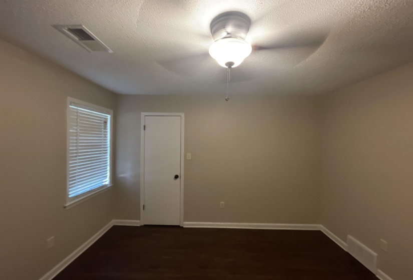 Room featuring dark wood-finish flooring, neutral wall tones, and white trim