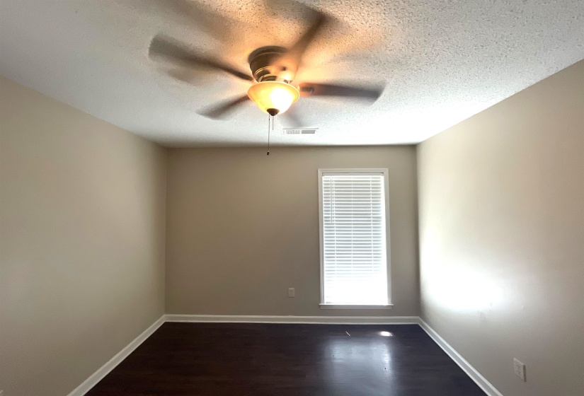 Room featuring a ceiling fan with integrated lighting, a tall window with blinds, wood-finish flooring, and light-toned walls