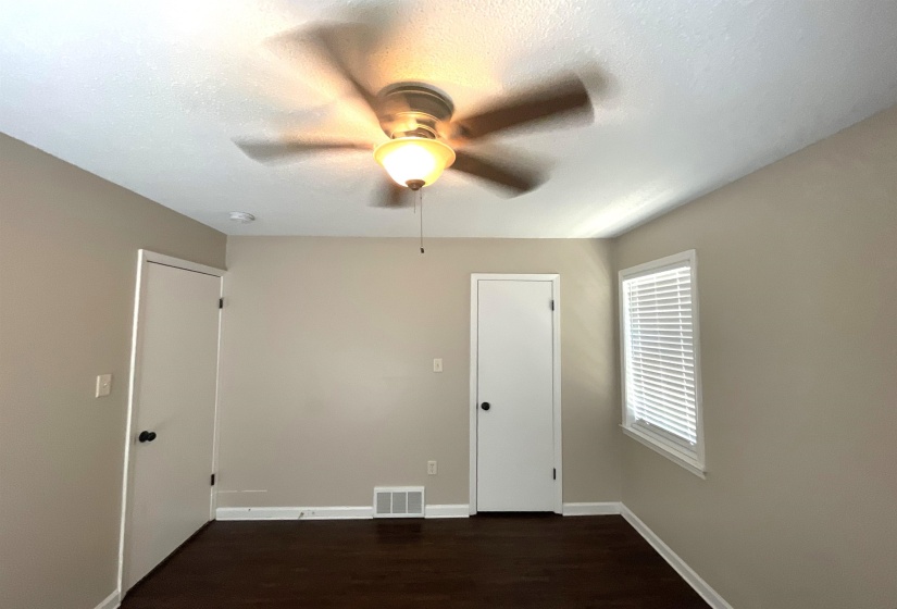 Interior space featuring a ceiling fan with integrated lighting, wood-finish flooring, and neutral wall tones