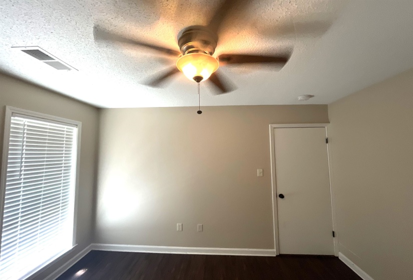 Room featuring a ceiling fan with integrated lighting, a window with horizontal blinds, neutral wall paint, and dark wood-finish flooring