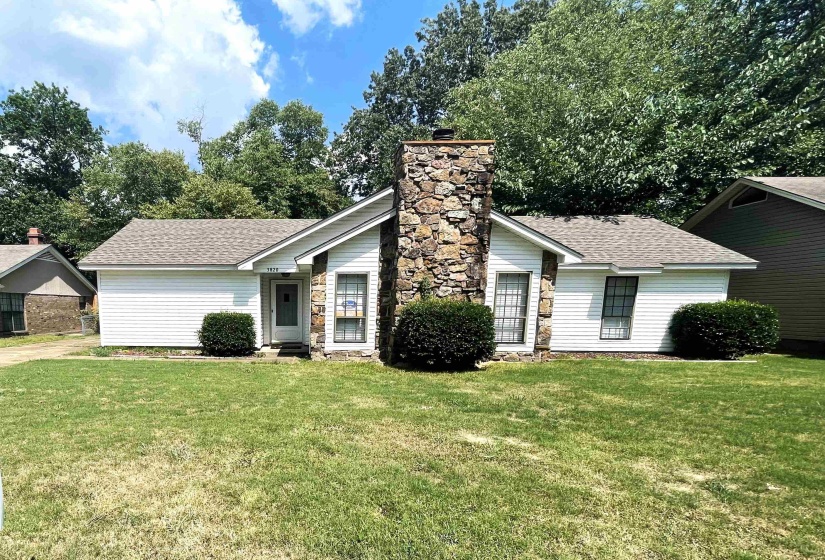 Single-story residence featuring a stone chimney facade, white siding, and a gabled roof