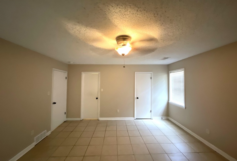 Neutral-toned room featuring ceramic tile flooring, a window with horizontal blinds, and a ceiling fan with integrated lighting