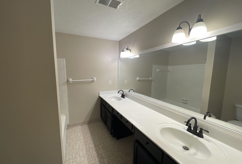 Double vanity with integrated sinks and dark cabinetry, set against a full-width mirror