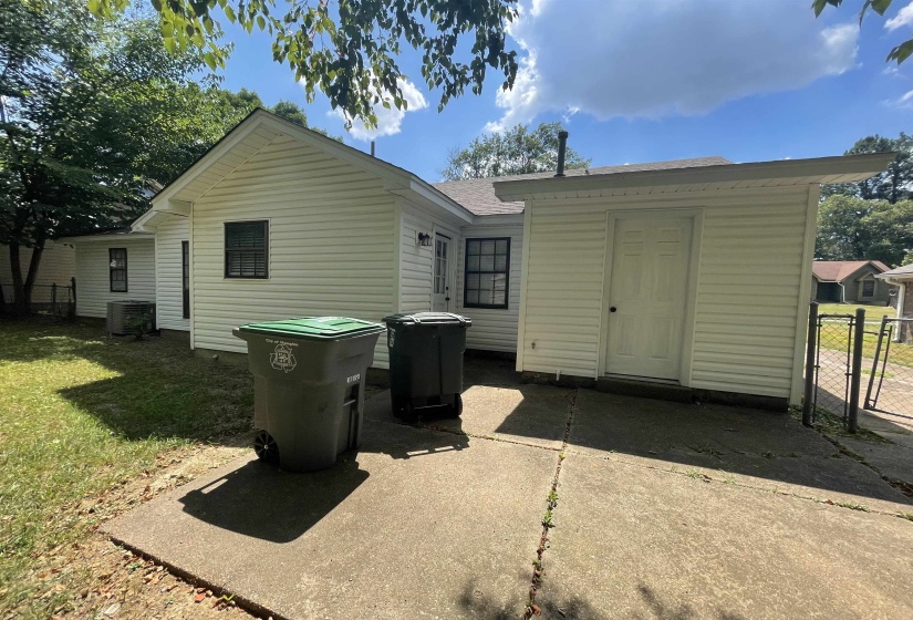 Rear exterior featuring white vinyl siding, a concrete patio, and a dedicated utility shed with a side entrance
