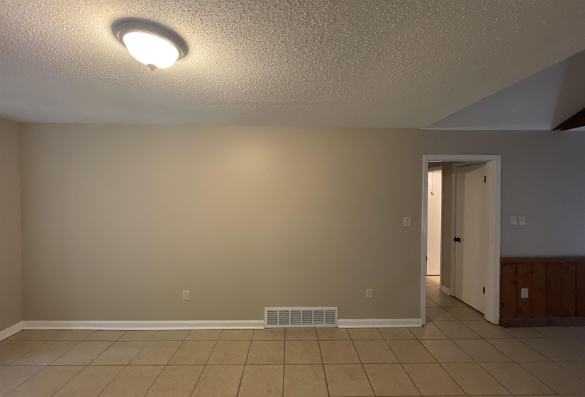 Interior room featuring neutral-toned walls, tile flooring, and a ceiling-mounted light fixture