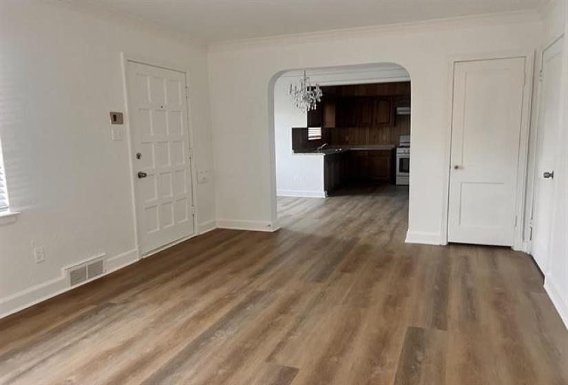 Spacious living area featuring wood-finish flooring, white baseboards, and an arched doorway