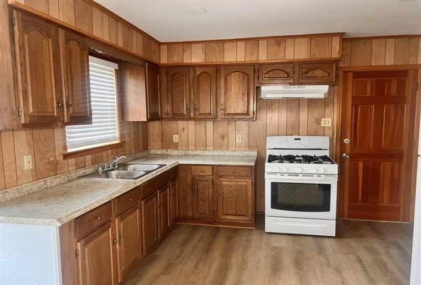 Kitchen featuring wood-finish paneling, wood-finish cabinetry, and a double basin stainless steel sink
