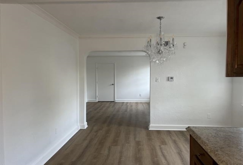 Open concept living area featuring a crystal chandelier and wood-finish flooring