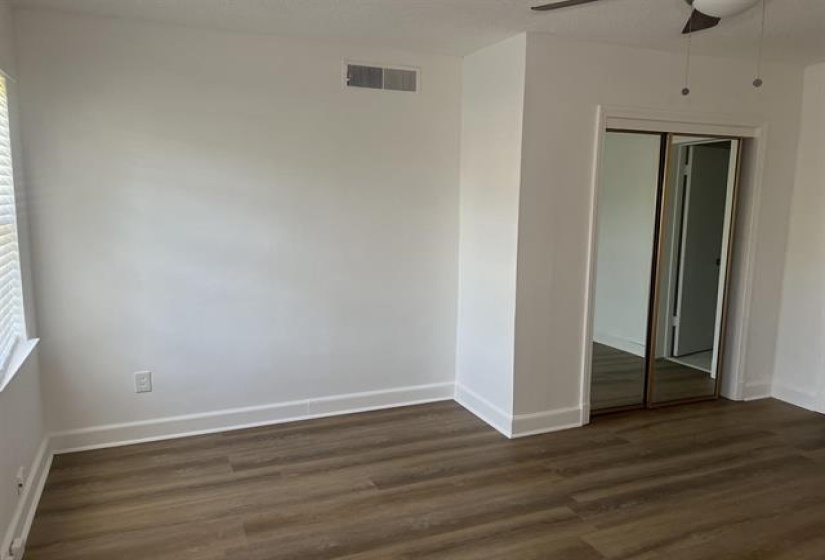 Spacious room featuring wood-finish flooring, white baseboards, and a ceiling fan